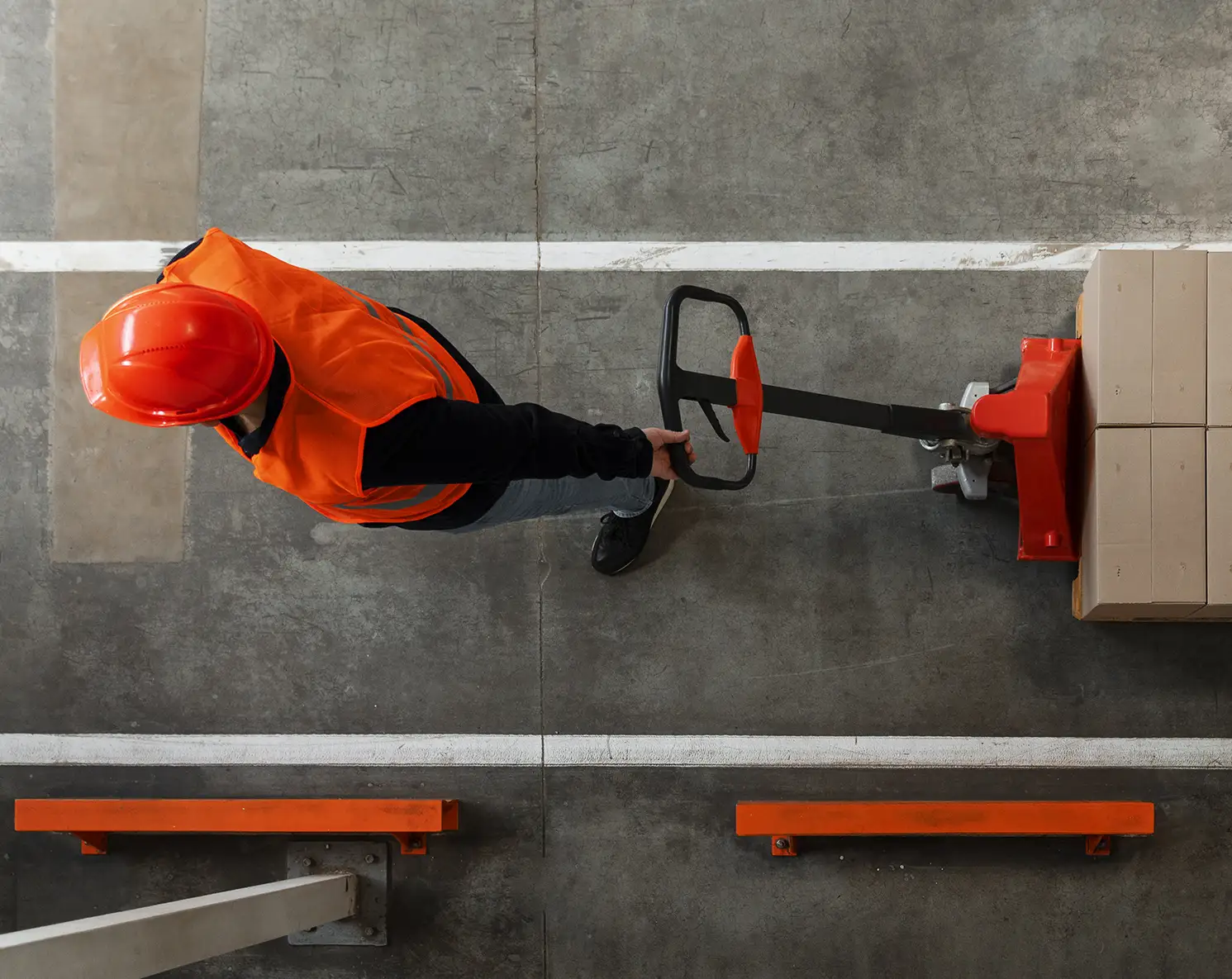 Elye Distribution – Overhead Pallet Jack Operation Overhead view of a worker moving a pallet with a pallet jack inside a warehouse.